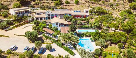 An aerial view of a resort with multiple buildings, a swimming pool, and a parking area.