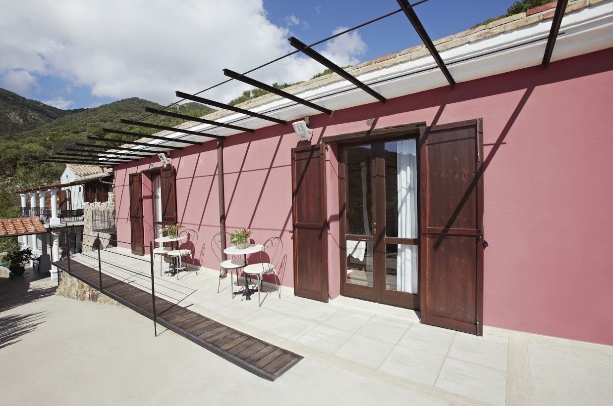 Un bâtiment rose doté d’un patio couvert, d’un espace extérieur aménagé pour s’asseoir et offrant une vue sur une montagne.