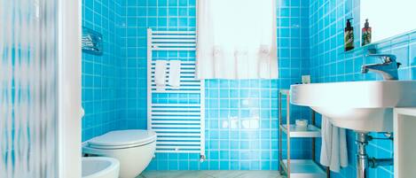 Un baño con azulejos azules, un lavabo blanco y un inodoro.