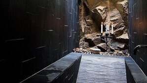 A modern bathroom with a stone wall, a skylight, and a candle holder. - Hotel Kullaberg (Molle)