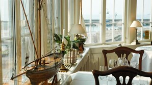 A dining area with a view of the sea, a ship model, and a table set for two. - Hotel Kullaberg (Molle)