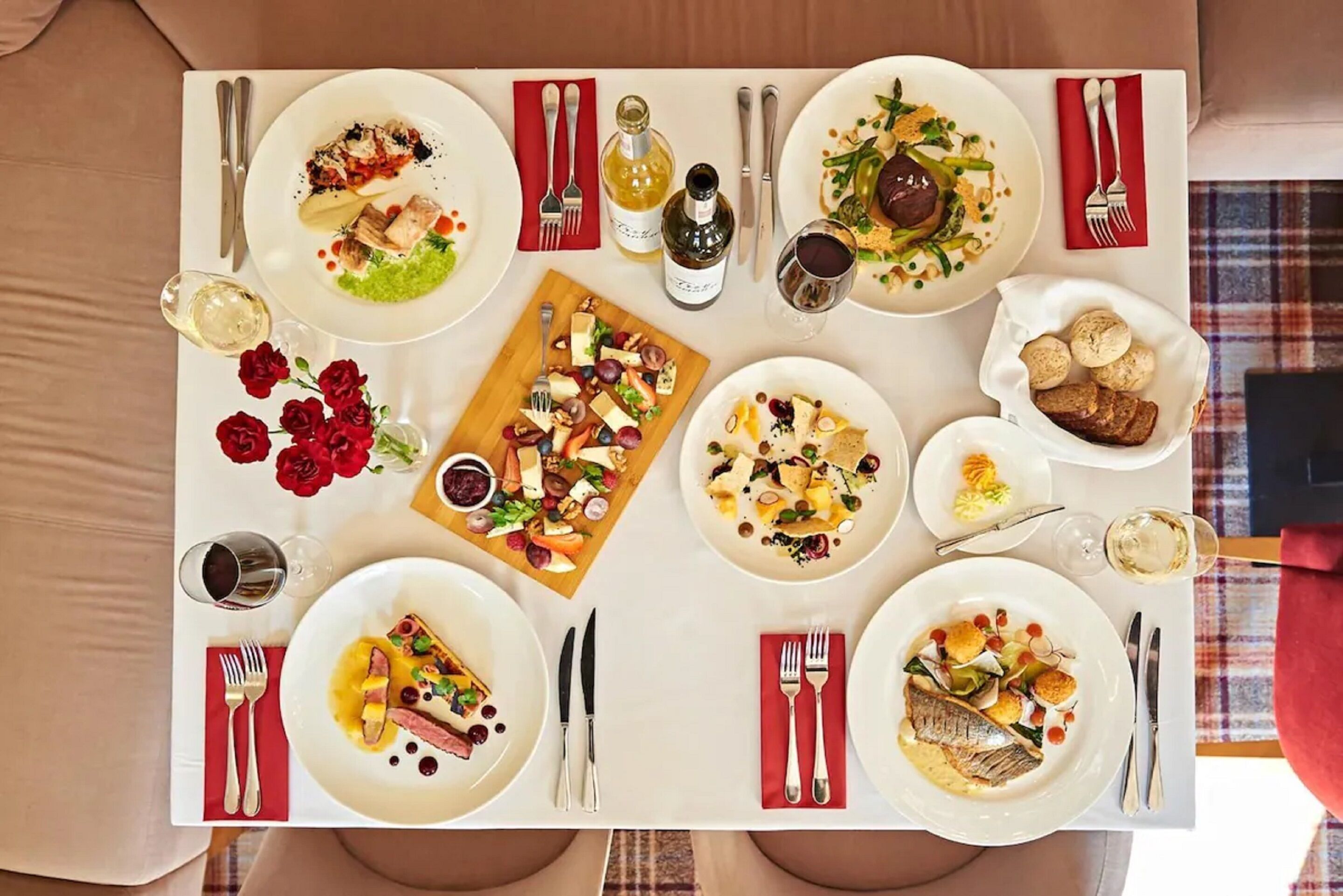 Una mesa de comedor preparada con diferentes platos, copas de vino y cubiertos.