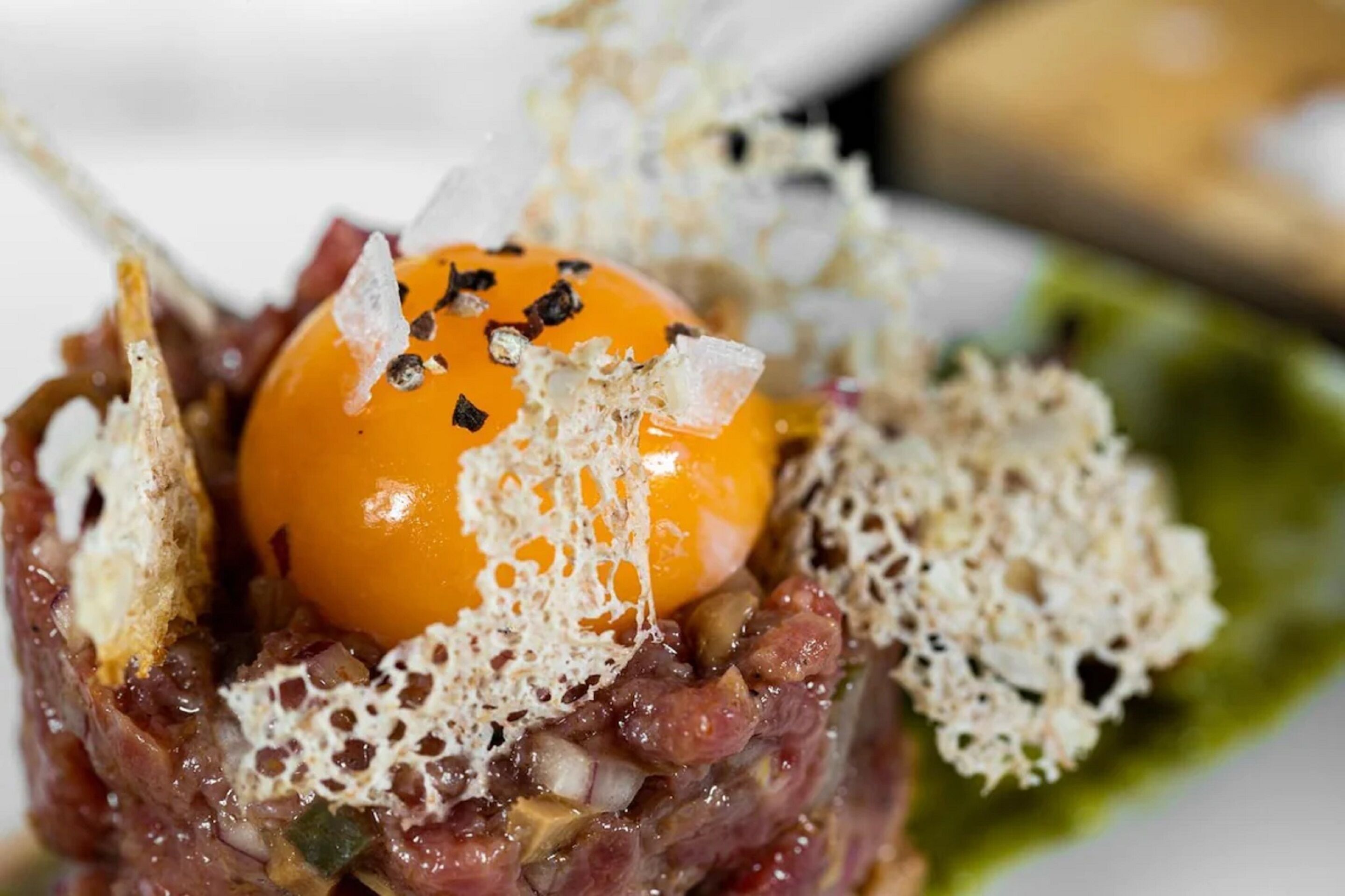 A dish with a raw meat base, an egg, and decorative elements.