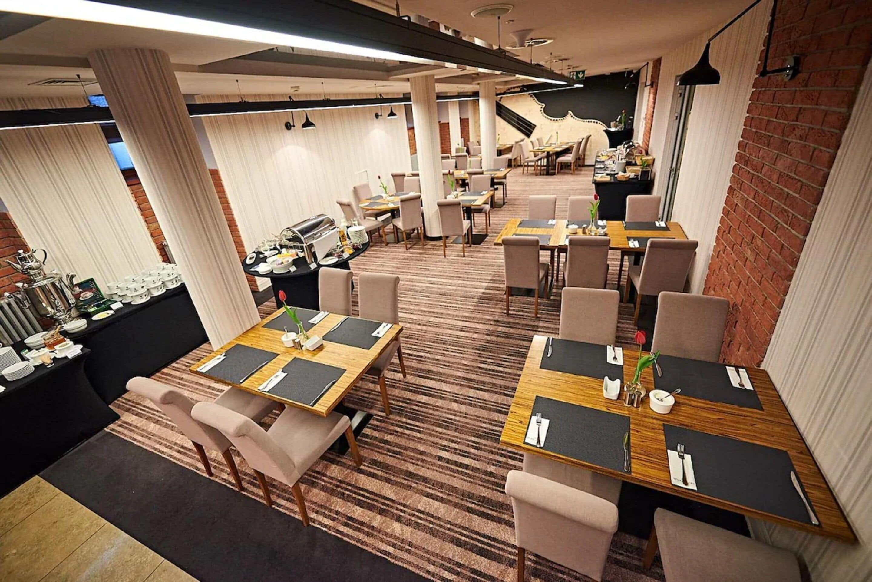 Een restaurant met meerdere tafels en stoelen, een buffetgedeelte en een metselwerk muur.