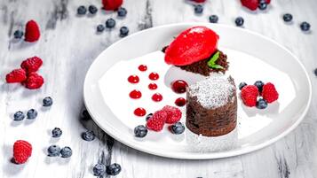 A dessert on a white plate with strawberries and blueberries.