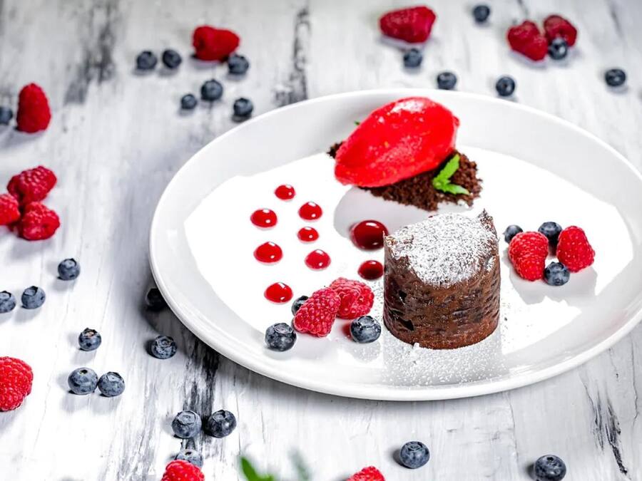 A dessert on a white plate with strawberries and blueberries.