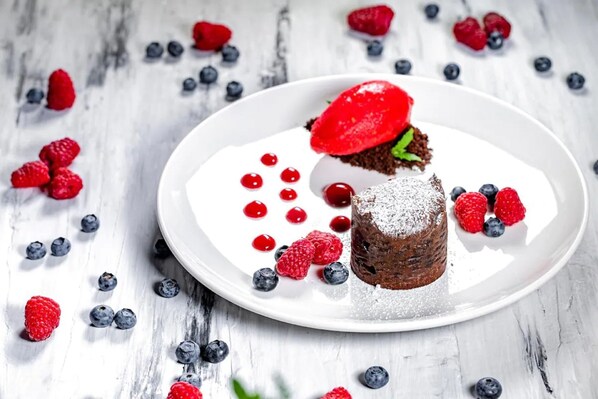 Un postre en un plato blanco con fresas y arándanos.