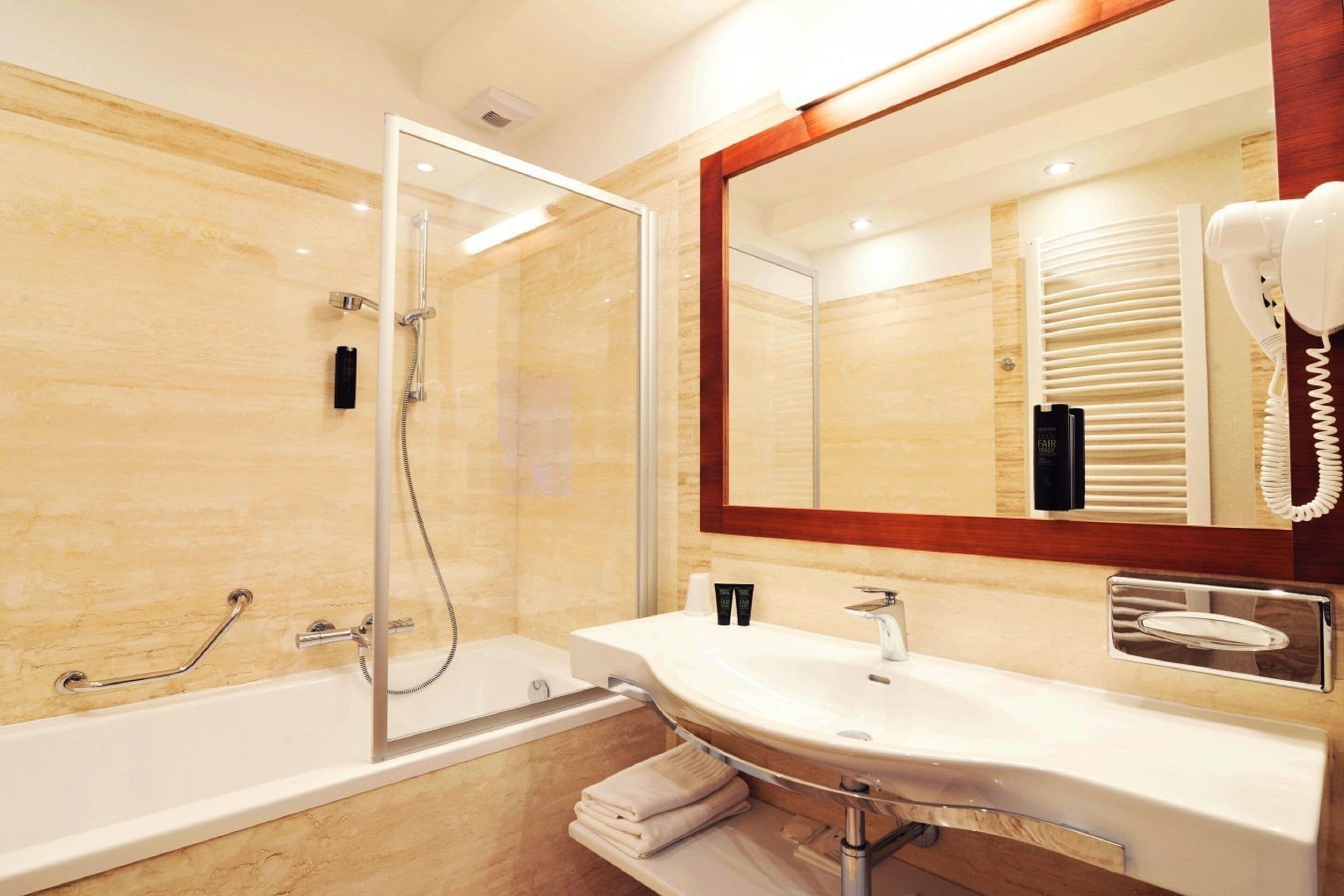 Un baño moderno con ducha envuelta en vidrio, un lavabo blanco y un espejo grande.