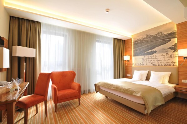 Una habitación de hotel con una cama grande, un escritorio con silla y una lámpara en la pared.