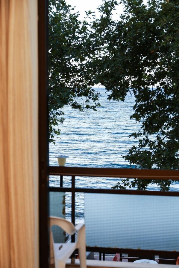 Une vue depuis une fenêtre donnant sur une étendue d’eau, avec une chaise et une table visibles à l’intérieur.