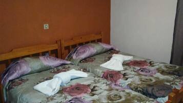 Una cama con cubrecama floral, cabecera de madera y aire acondicionado instalado en la pared.
