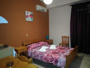 Une chambre à coucher avec un lit en bois, une table de chevet avec une lampe, une chaise et un tableau accroché au mur.