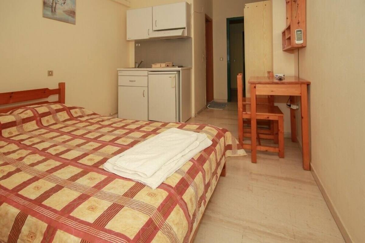 Un dormitorio con cama, una kitchenette pequeña y un escritorio de madera.