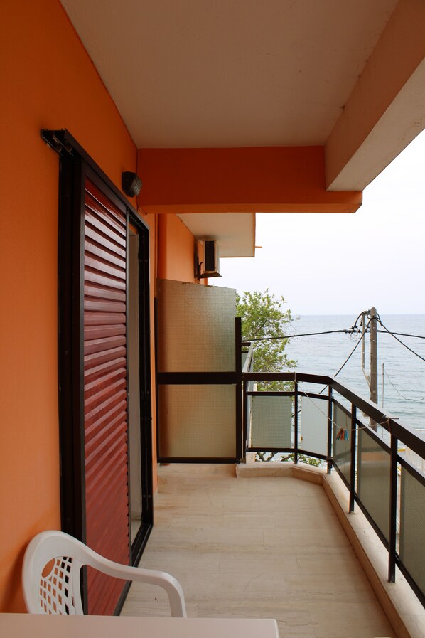 A balcony with a view of the sea, a table, and a chair. - Astir Rooms (Kefalonia)