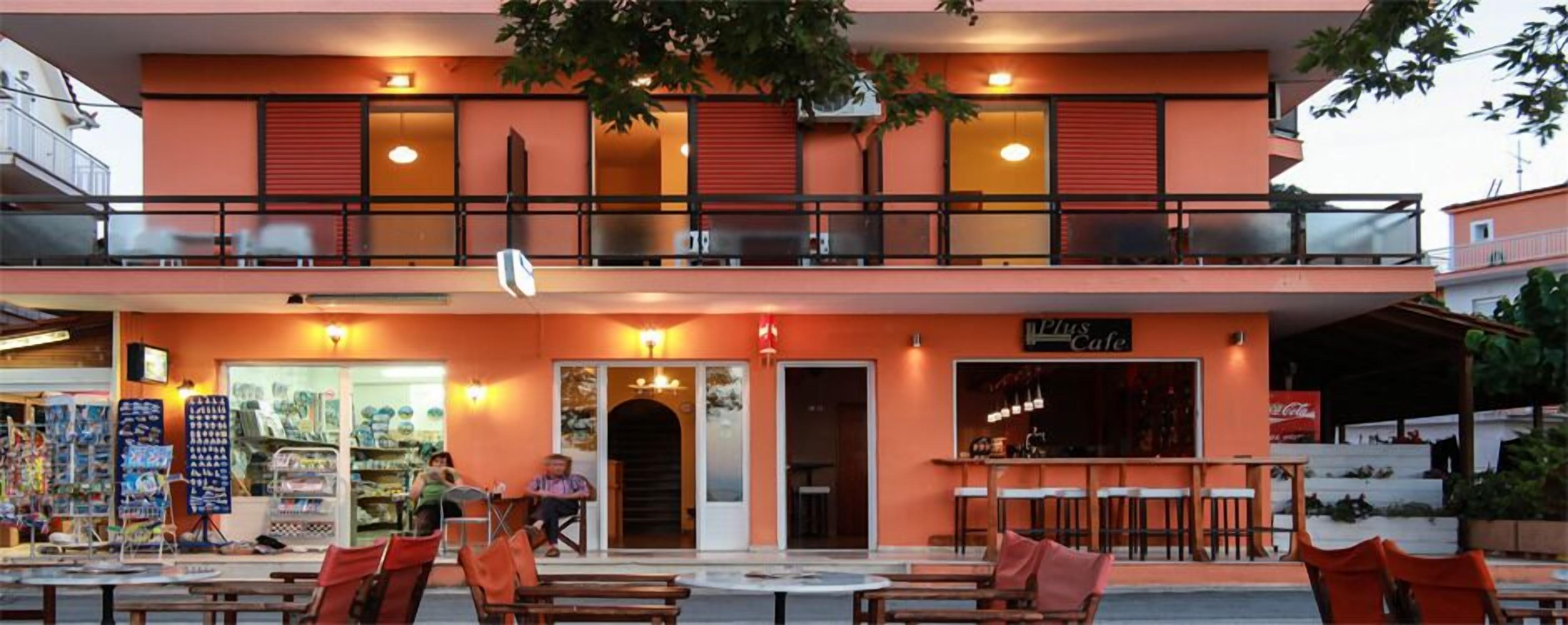 A two-story building with a cafe on the ground floor and a restaurant on the upper floor. There are outdoor seating areas with tables and chairs.