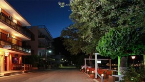 Un hotel de varios pisos con restaurante y bar en la planta baja, terraza al aire libre y fachada bien iluminada.