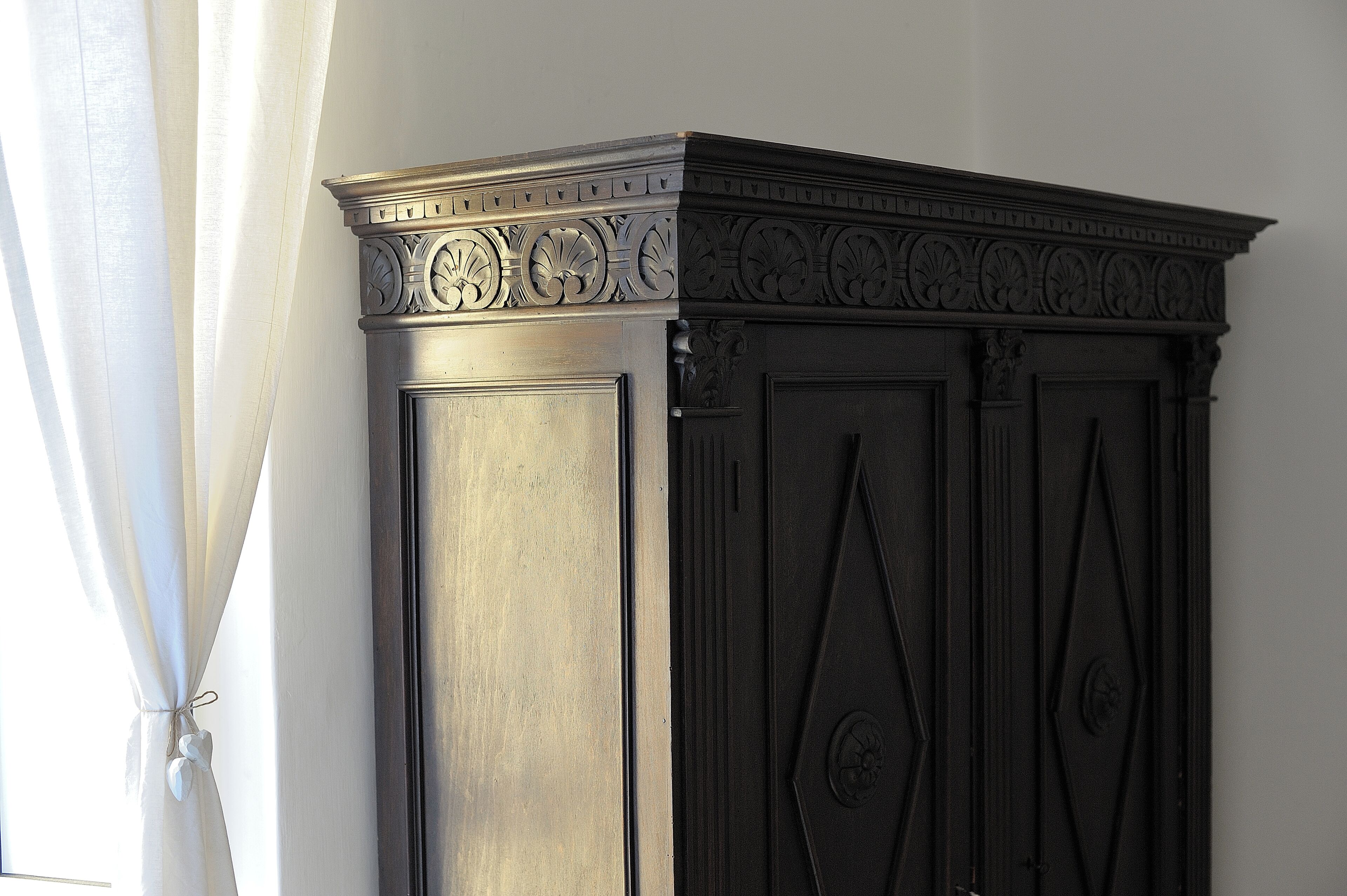 A dark wooden cabinet with intricate carvings and a decorative top.