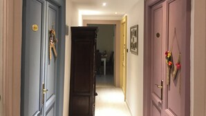 A hallway with three doors, each with a different color and a small decorative item on the door. - Aquarius Inn (Rome)