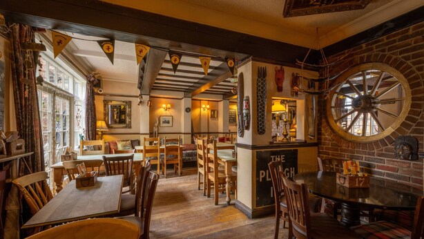 Un restaurant chaleureux avec des tables et des chaises en bois, un mur en briques et une grande fenêtre.