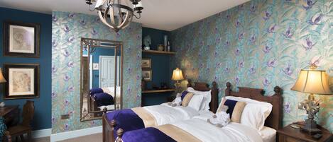 A bedroom with a large bed, a chandelier, a mirror, and a dresser.