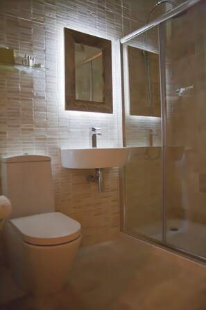 A bathroom with a toilet, a sink, and a glass-enclosed shower.