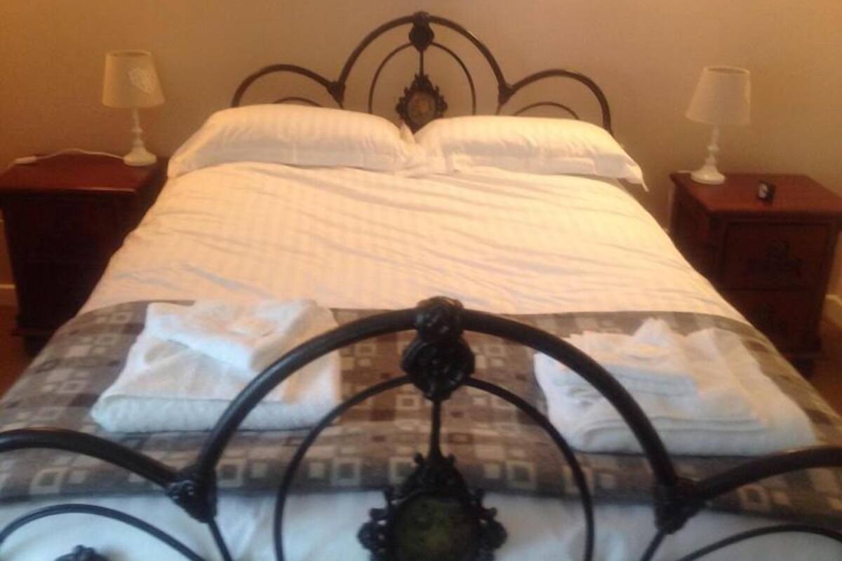 A bed with a metal frame, white bedding, and two bedside tables with lamps.