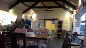 A cozy restaurant with wooden furniture, stone walls, and a stone floor. - Four Seasons Bed and Breakfast (Carmarthen)