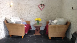A cozy room with two wicker sofas, a small table with a vase of flowers, and a heart-shaped decoration on the wall. - Four Seasons Bed and Breakfast (Carmarthen)
