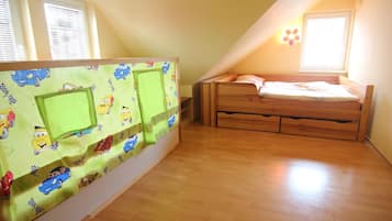 A bedroom with a wooden bed, a green wall with cartoon cars, and a window with blinds.