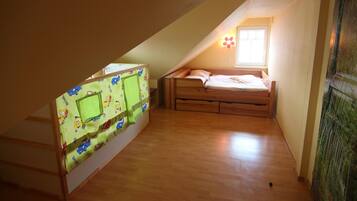A small attic bedroom with a bunk bed, a window, and a green curtain.