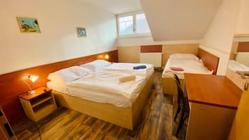 Ein Zimmer mit zwei Betten, einem Schreibtisch, einem Nachttisch und einem Fenster.