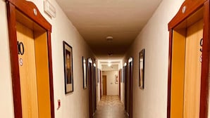 A hotel hallway with wooden flooring, multiple doors, and framed pictures on the walls. - Hotel Restaurant Švejk (Bublava)