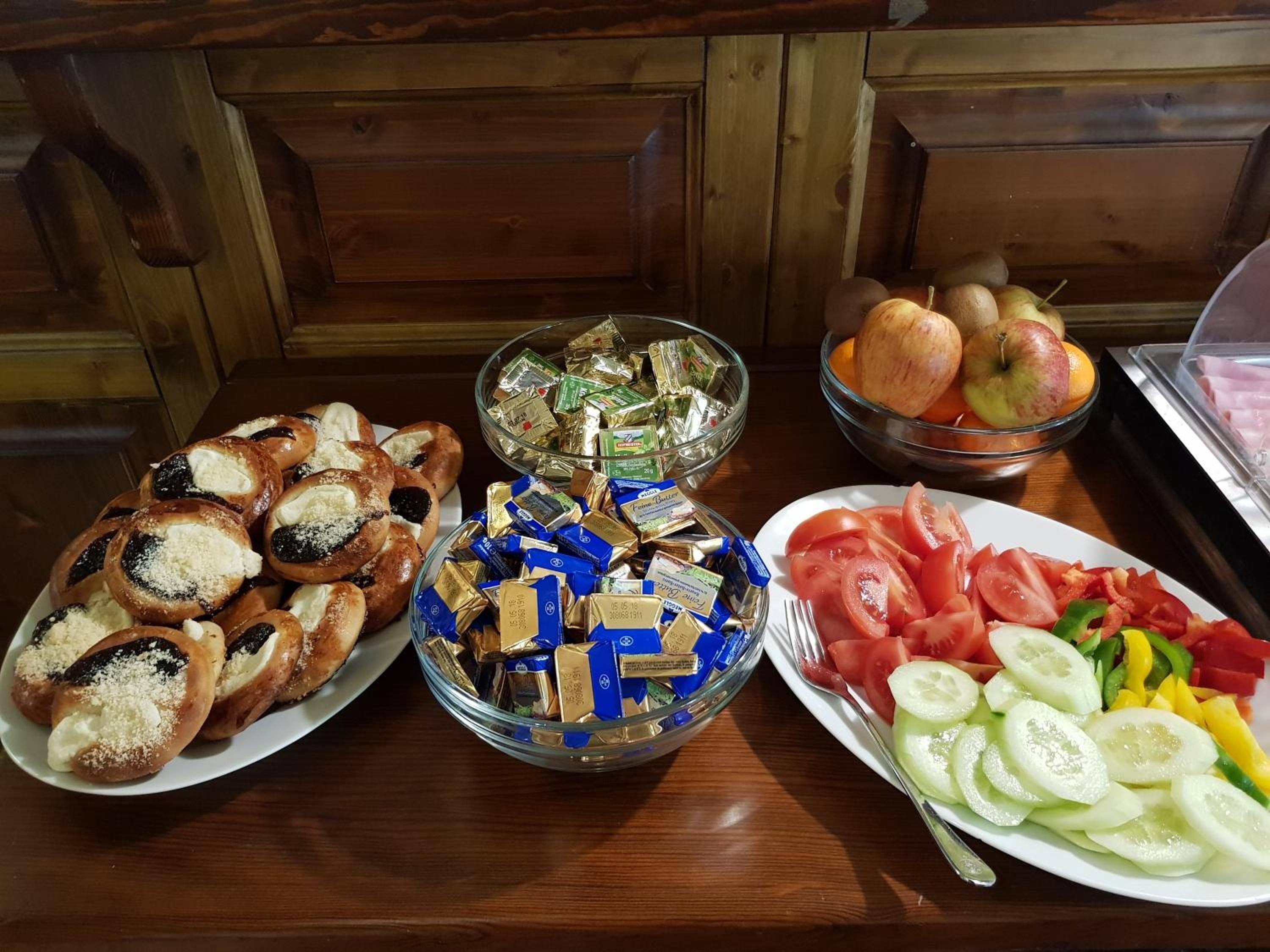 Una mesa con platos de pasteles, bombones y frutas y verduras en rodajas.