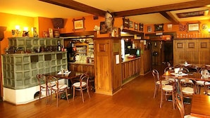 A cozy bar area with wooden furniture, a fireplace, and various decorations on the walls. - Hotel Restaurant Švejk (Bublava)