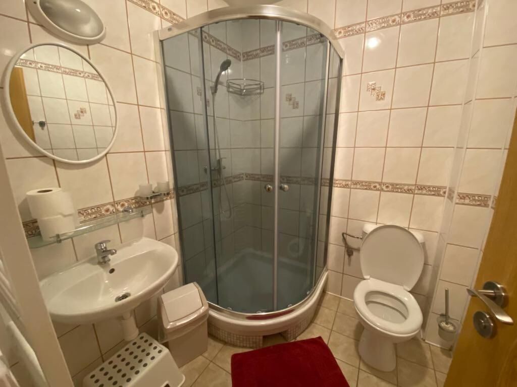 Un baño con ducha de vidrio, lavamanos, inodoro y espejo.