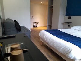 Una habitación de hotel moderna con una cama, un escritorio con computadora, una silla y una mesita.