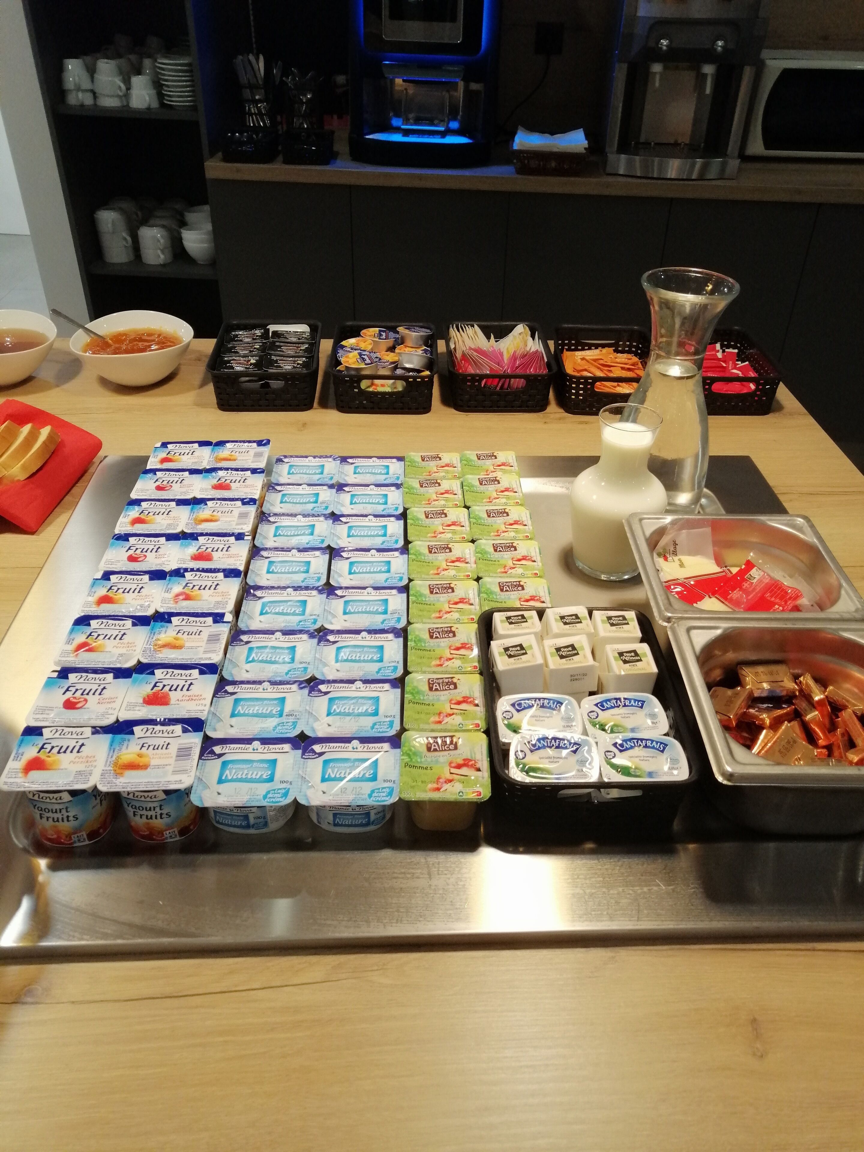 A buffet table with various food items including yogurt, fruits, and condiments.