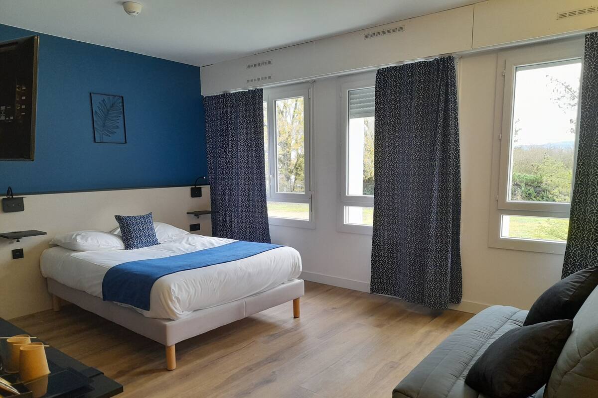 Un dormitorio moderno con una cama, una mesita de noche, una silla y una ventana con cortinas.