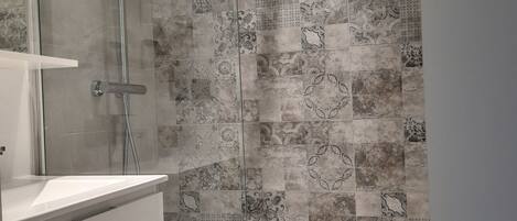 Un baño con ducha, lavamanos y espejo.