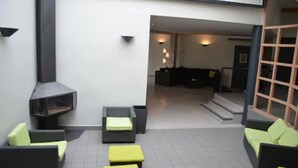 A modern outdoor seating area with a fireplace, sofas, and a staircase leading to an interior living space. - Le Riccoty (Blyes)