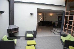 Un espacio al aire libre moderno con asientos, una chimenea, sofás y una escalera que conduce a un ambiente interior.