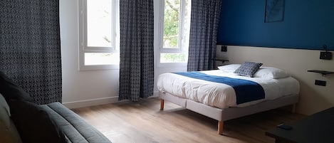A bedroom with a bed, a sofa, and a desk.