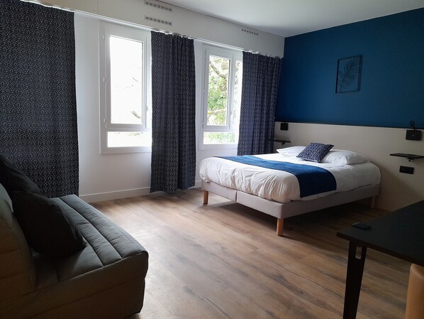 A bedroom with a bed, a sofa, and a desk.