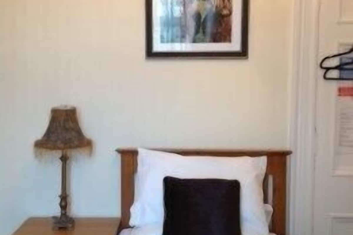 A bedroom with a bed, a nightstand, a lamp, and a framed picture on the wall.