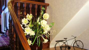 A wooden staircase with a vase of white flowers and a bicycle.