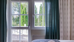 Una habitación con cama, ventana y vista a árboles.
