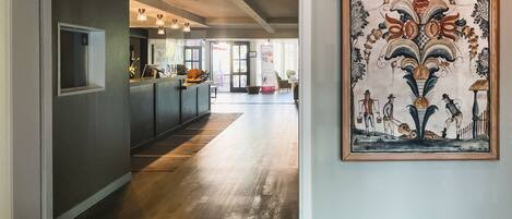 A hallway with a reception desk, a framed artwork on the wall, and a wooden floor.