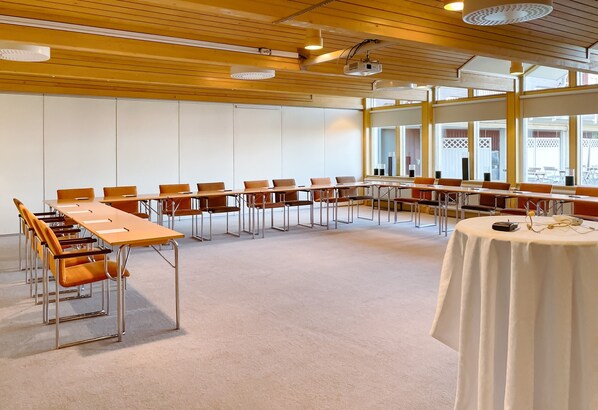 A conference room with long tables and chairs, large windows, and a carpeted floor. - Gyllene Hornet (Tallberg)