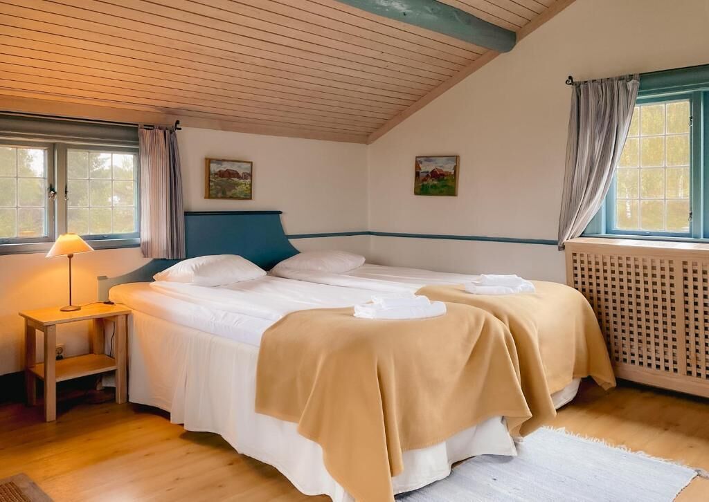 A bedroom with a bed, a nightstand, a lamp, and a window with curtains.