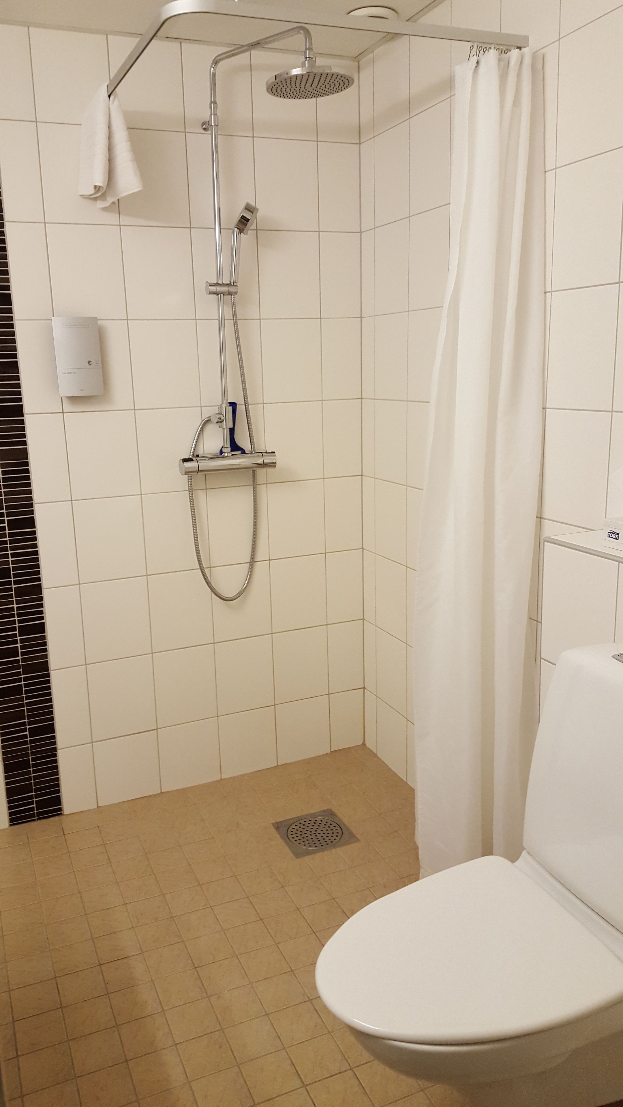 Un bagno con doccia, toilette e un asciugamano appeso al muro.